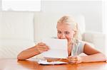 Happy woman reading a letter in her living room