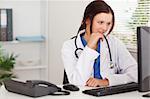 A female doctor in office is looking to pc screen