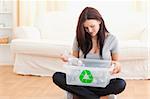 Cute woman putting bottles in a recycling box in her home