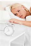 Portrait of a woman awaken by an alarmclock  in her bedroom