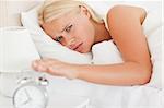 Cute woman awaken by an alarmclock in her bedroom