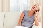 Laughing woman speaking on the phone in her living room