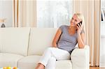 Happy woman speaking on the phone in her living room