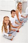 Happy smiling kids doing yoga relaxation at home with their mother - focus on the little girl