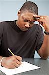 African-american adult education student struggles with test anxiety as he takes an exam.