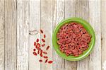 dried Tibetan goji berries (wolfberries) in a green ceramic bowl on a grunge white painted wood surface