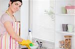 Woman washing the dishes looking into the camera in the kitchen