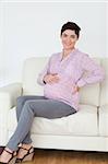 Smiling pregnant woman sitting on a sofa in a waiting room