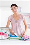 Smiling Woman ironing clothes in a utility room