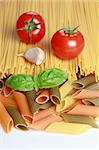 Ingredients for a pasta meal including tomatoes, garlic, basil and different kind of pasta