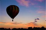 Hot-air balloon floating against a reddish dawn or dusk sky