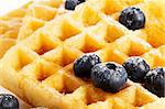 closeup from waffles with sugar covered blueberries and syrup