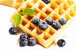 waffles with sugar covered blueberries melisss and syrup from top on white background