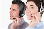 Close up of workers speaking through headsets against a white background