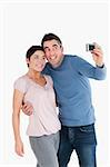 Portrait of a couple taking a picture of themselves against a white background