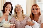 Charming women lounging on a sofa watching a movie in a living room