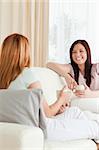 Chatting young women sitting on a sofa with cups in a living room