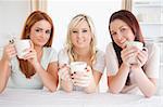 Cute Women sitting at a table with cups in a kitchen