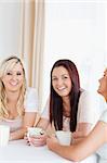 Gorgeous young Women sitting at a table with cups in a kitchen