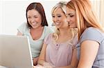 Smiling women sitting on a sofa with a laptop in a living room