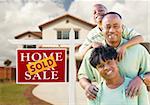 Happy African American Family in Front of New House and Sold Real Estate Sign.