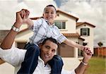 Playful Hispanic Father and Son in Front of Beautiful House.