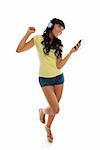 A happy vivacious girl playing music on a portable player and dancing