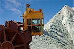 A wheel digger, used to excavate minerals at a mine in front of a huge heap of iron ore