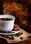 Cup of coffee and coffee beans in front of rustic wall