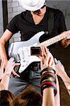 Rock guitarist playing in front of a cheering crowd.