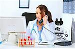 Concerned medical doctor woman talking on phone and looking in monitor