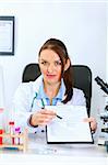 Medical doctor woman sitting at office table with document and pen for signing