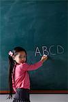 young girl writing on chalk board