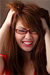 Head shot of woman wearing glasses and messing up her hair and smiling