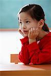 Portrait of young girl with hands on her face looking up