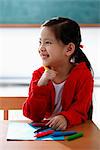 Young girl holding crayon and smiling