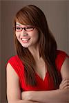 Young woman in red dress wearing red sunglasses looking away and smiling