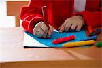 cropped shot of young girl coloring with crayons