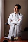 male doctor standing at his desk looking out window