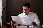 Man sitting at desk looking at paper