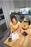 Femme assise dans la cuisine avec factures, portrait