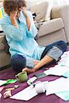 Worried woman sitting on floor with bills