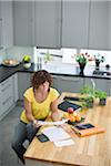 Femme assise dans la cuisine avec des factures