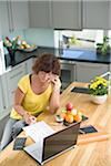 Woman sitting with bills and talking on mobile phone