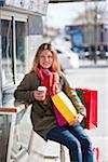 Young woman taking break from shopping, drinking takeaway coffee