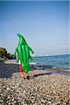 Boy walking on beach with inflatable