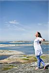 Woman standing on rock with arms up