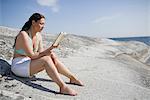 Femme assise sur rocher et lecture livre