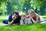 Eltern mit Sohn im Park liegen und Blick in die Kamera