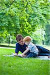 Father reading book to son in park